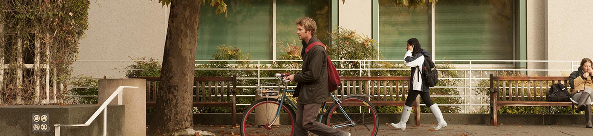 Student walks bike past Shields Library